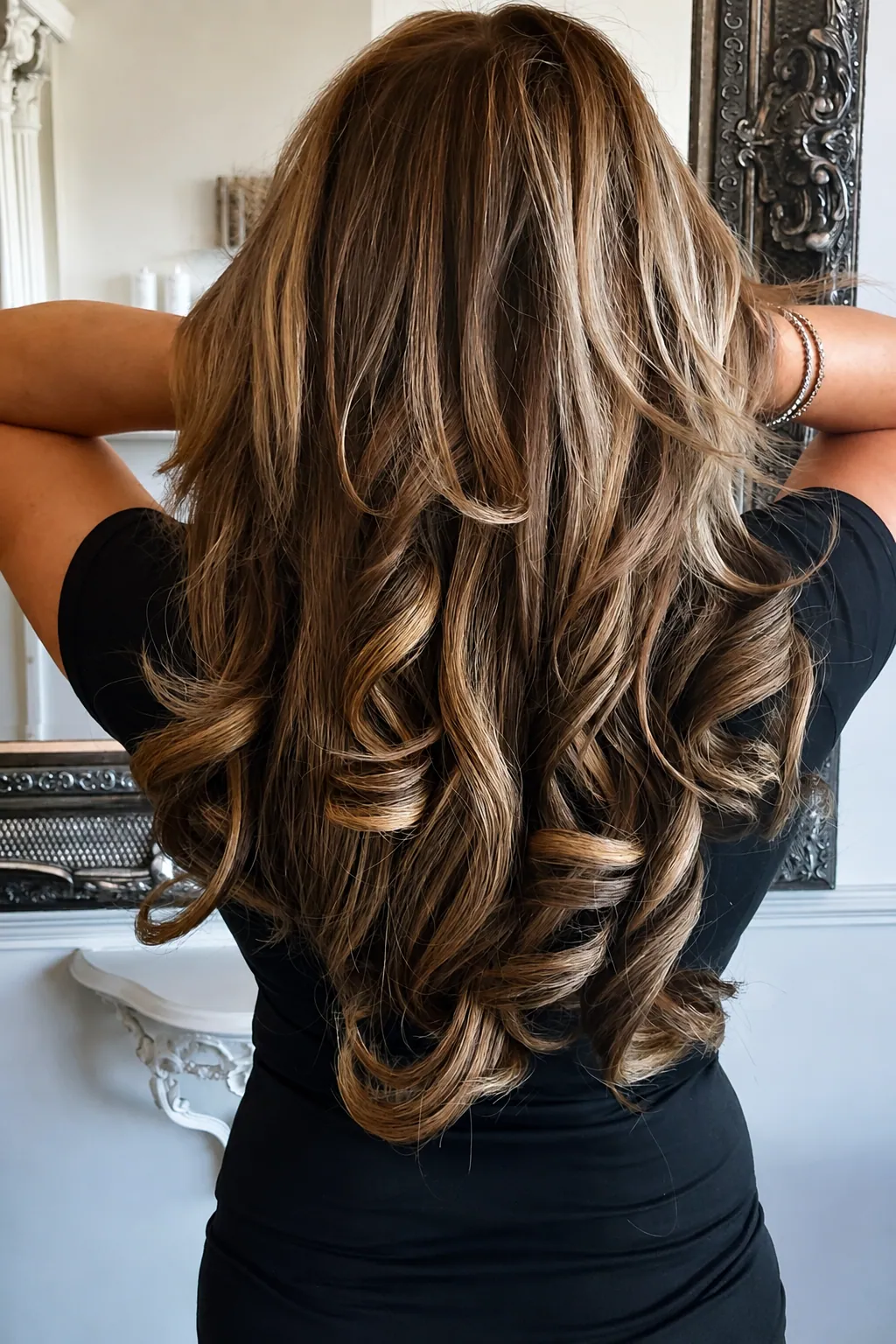 Back view of long, layered brunette hair with soft highlights and a voluminous blow-dry finish, styled at Esther Alexander