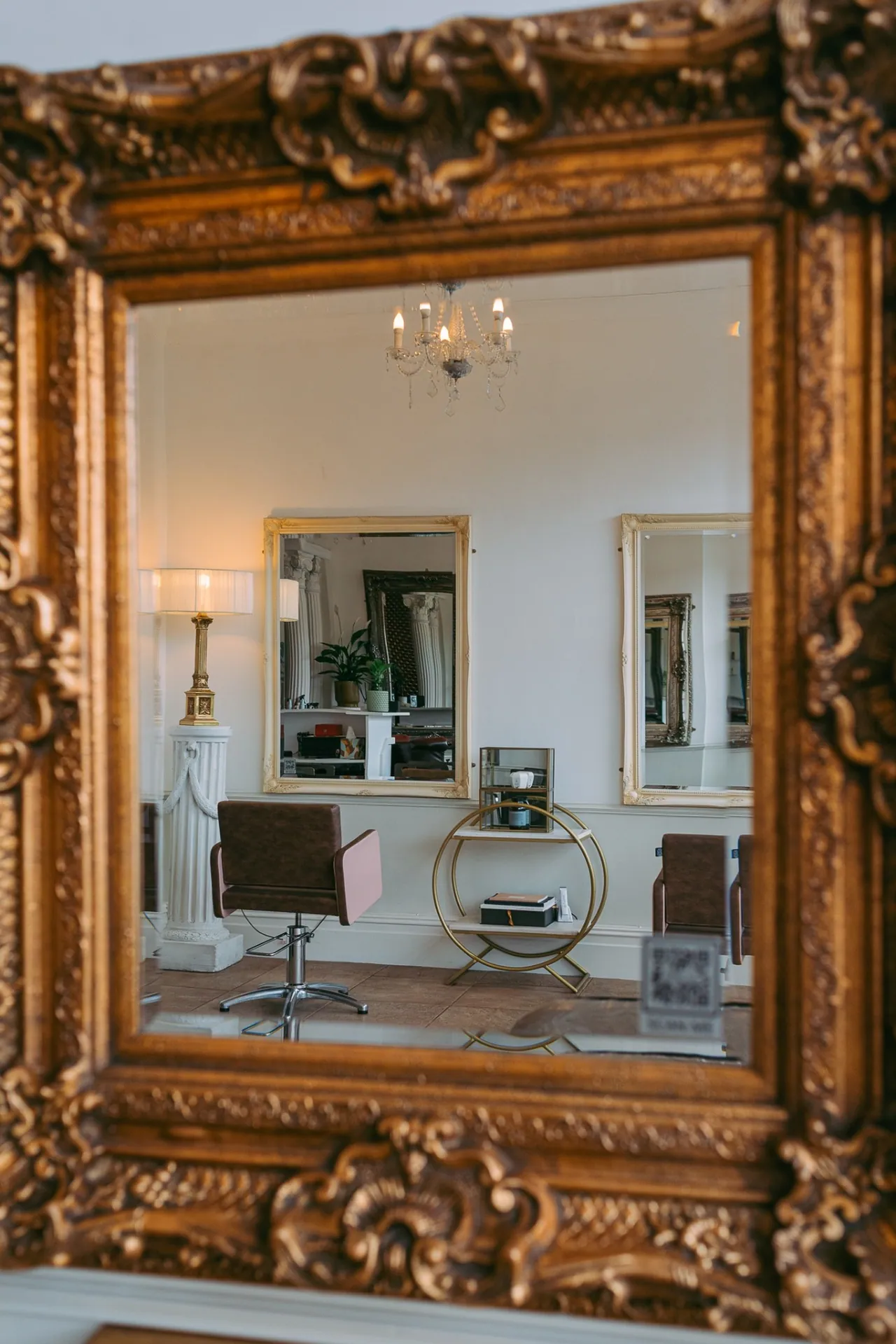 Ornate gilded mirror reflecting the salon interior