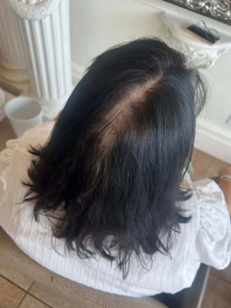 Grey regrowth along the parting of dark hair before root tint