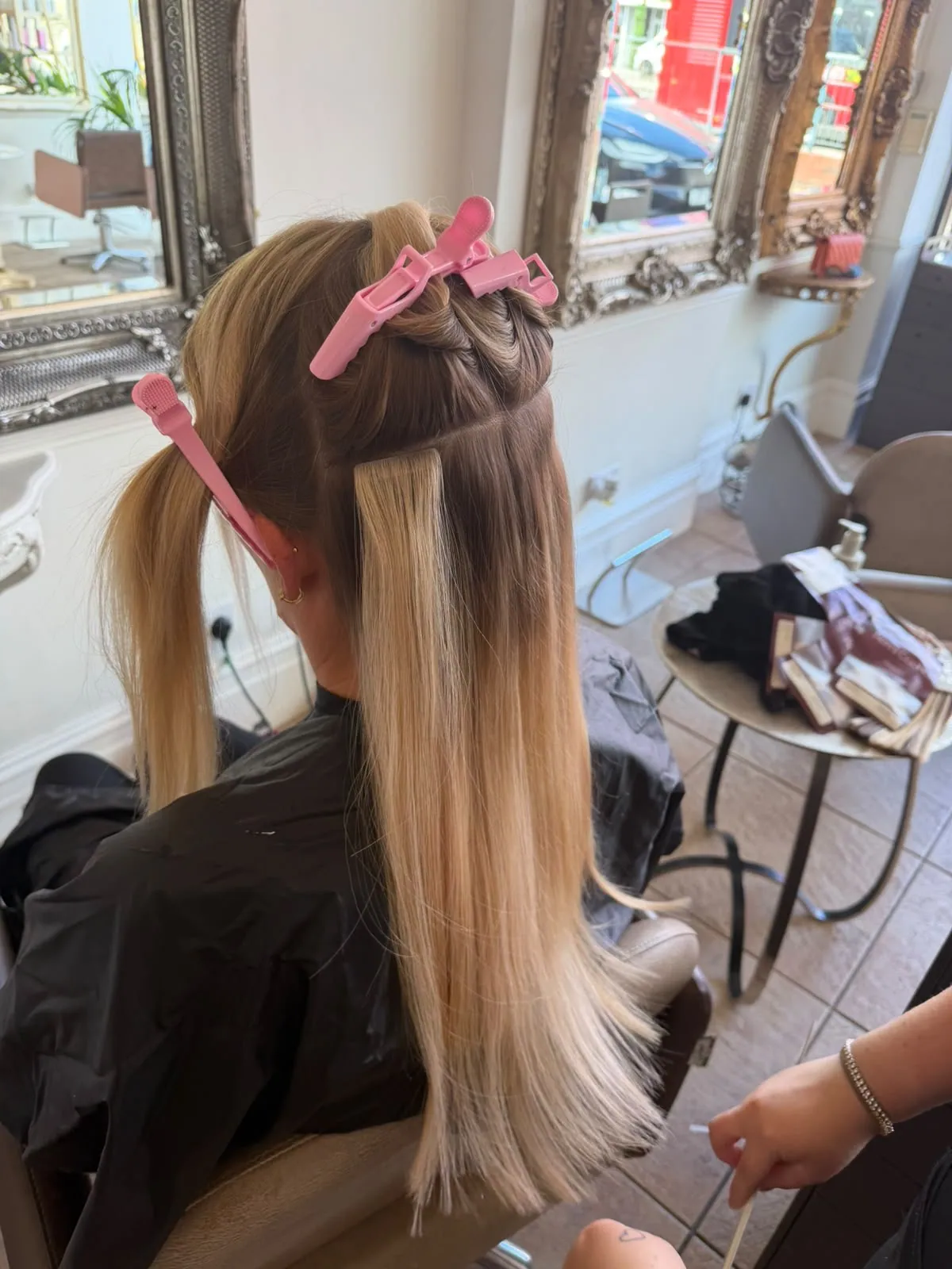 Close-up of blonde tape hair extensions being applied in the salon at Esther Alexander